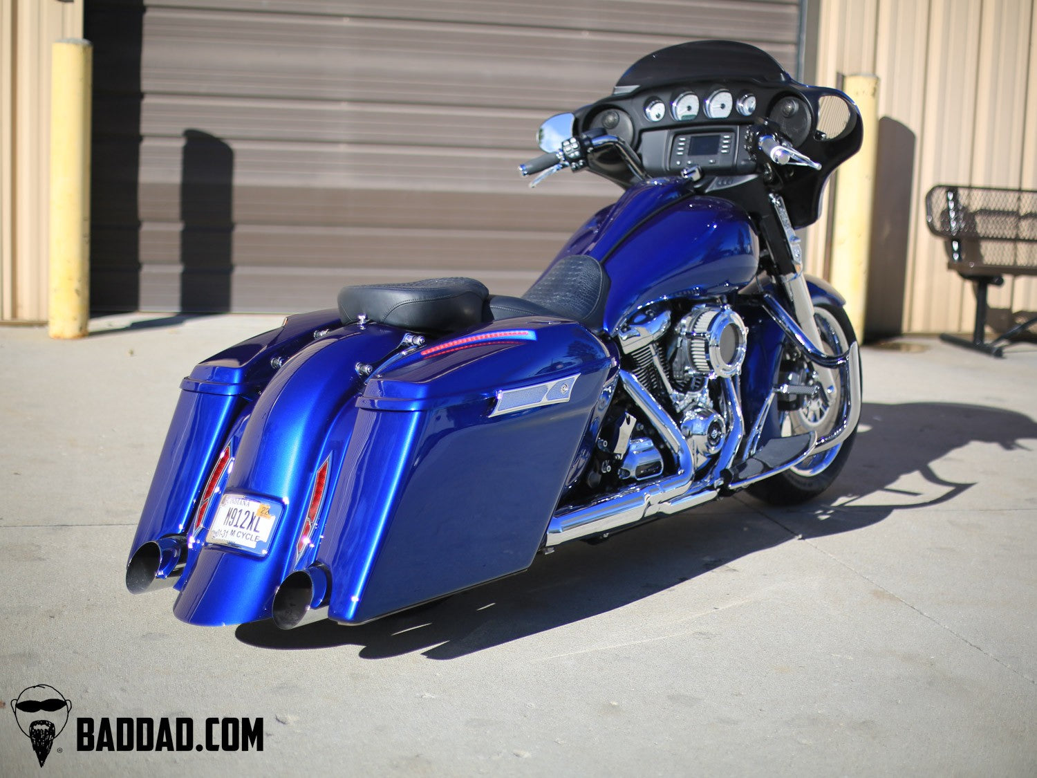 Custom saddlebag lid on a blue Street Glide parked outside the shop