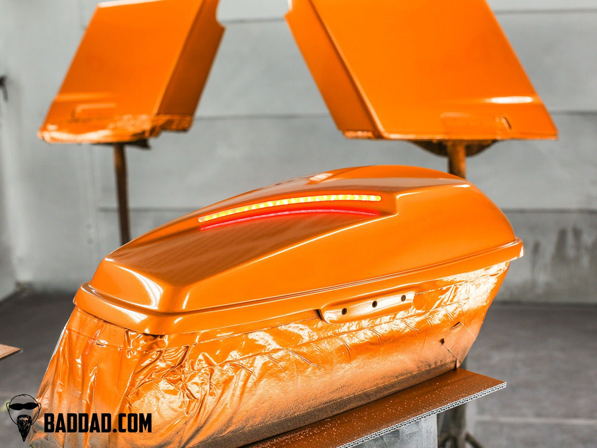 Orange competition saddlebag lid and matching fender in the paint booth for a Road Glide